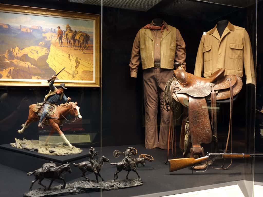 a display case with a cowboy outfit and horse figurines