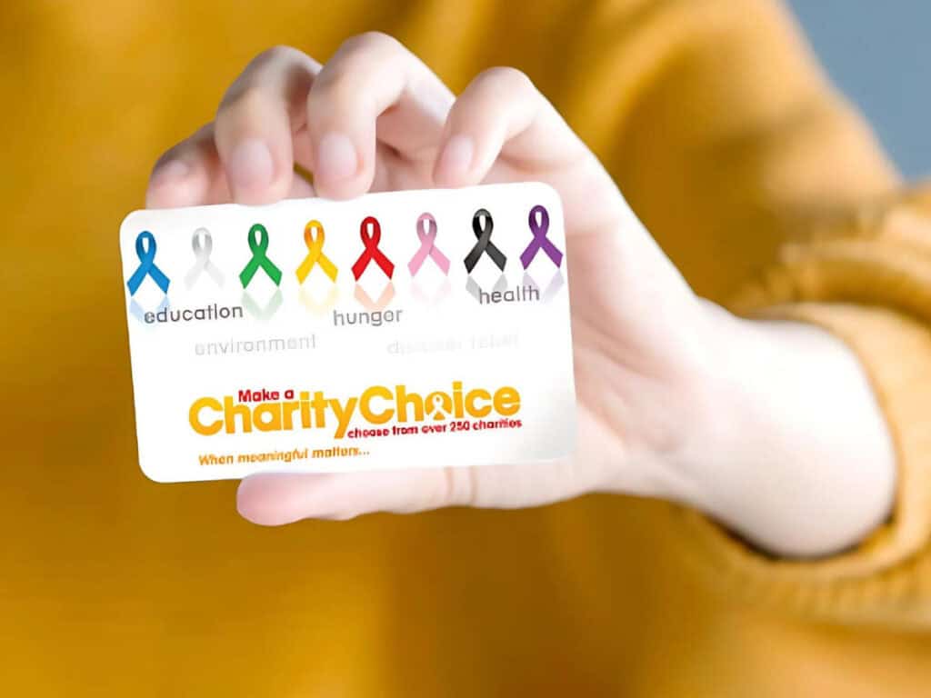 girl in yellow sweater holding up a charitychoice gift card